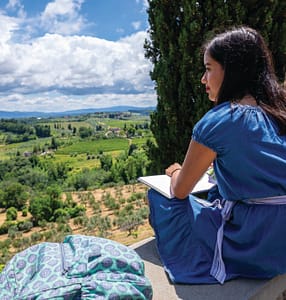 Two students sitting on ledge staring at countryside