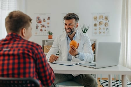 One mid adult doctor talking to teenage patient about eating healthy food