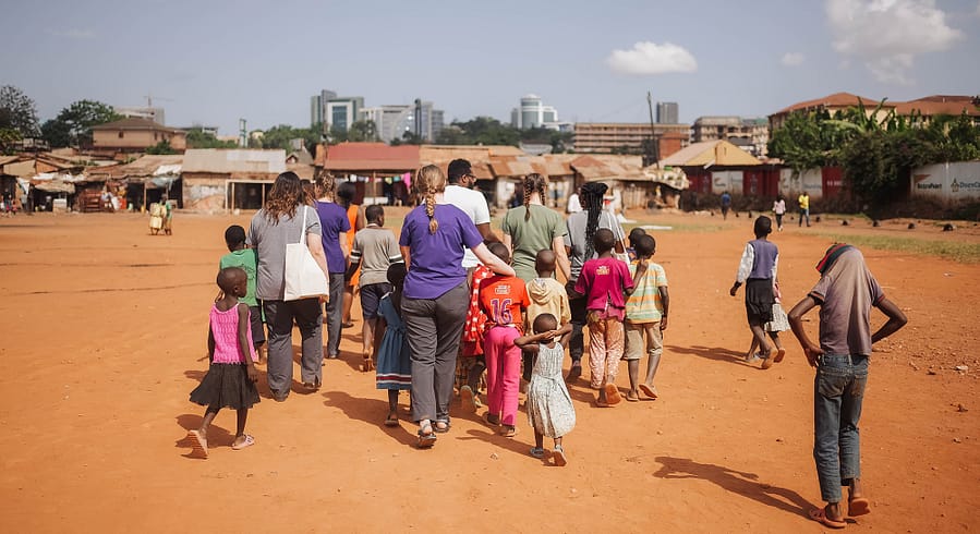 ACU speech pathology students and other volunteers with the nonprofit organization Hope Speaks walk with a group of Ugandan children on their way to do home visits.