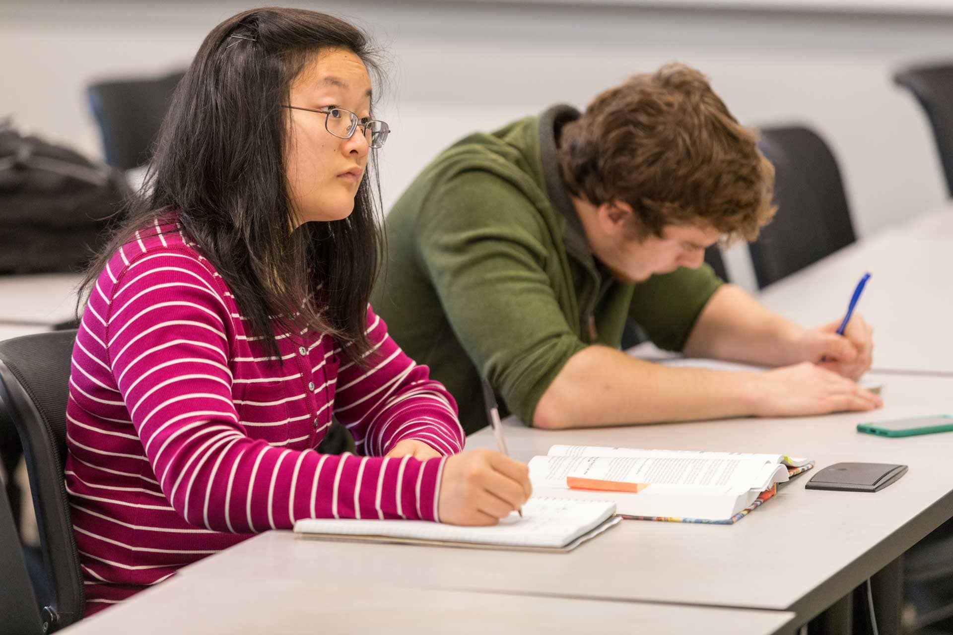 Two students taking notes in a math class