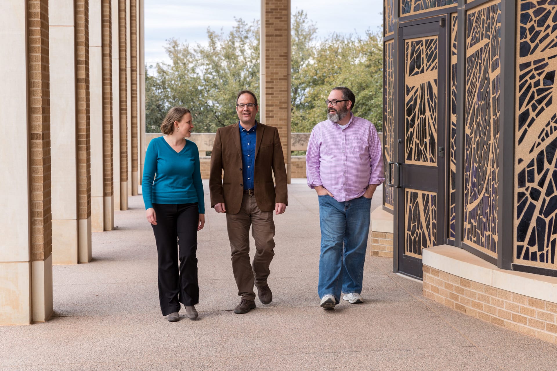 Three professors are walking outside of a building and chatting, Graduate School of Theology