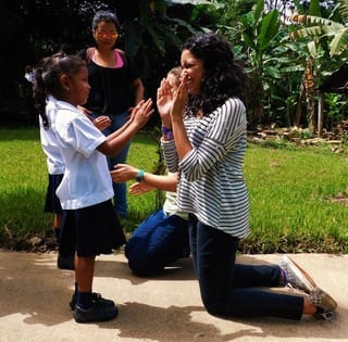 Renique Rodriguez kneeling with a child - ministry