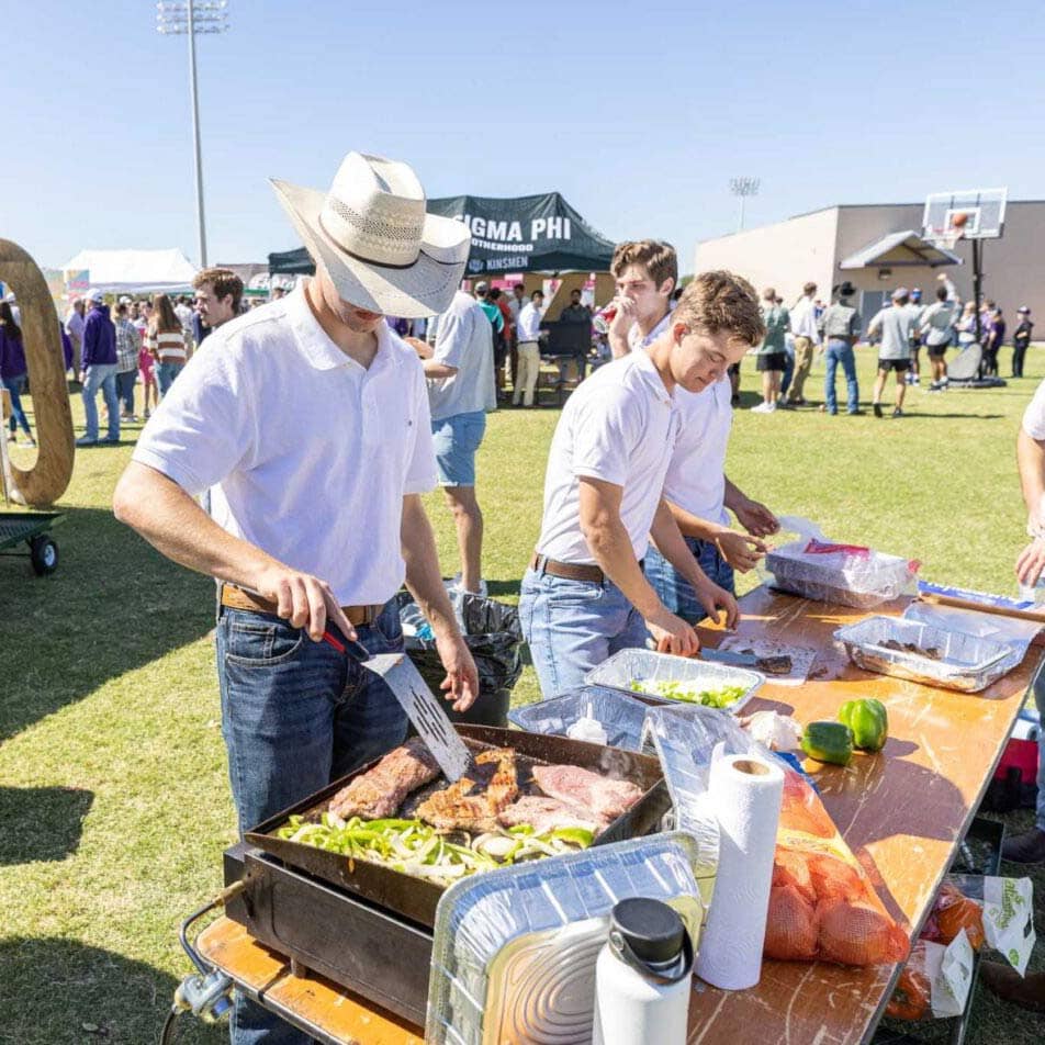 Students serving grilled food at a Greek Life event at ACU