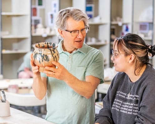 ACU Art student listens as a professor critiques her pottery