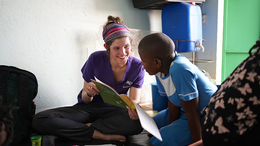 ACU student reading to a boy in Uganda